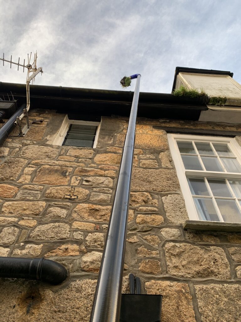 Gutter clearing near the seaside with succulents and grass clogging the gutters